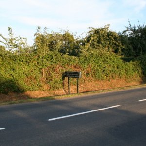 Outside Orglandes Cemetery showing small bocage type hedgerow with ditch at side of the road.