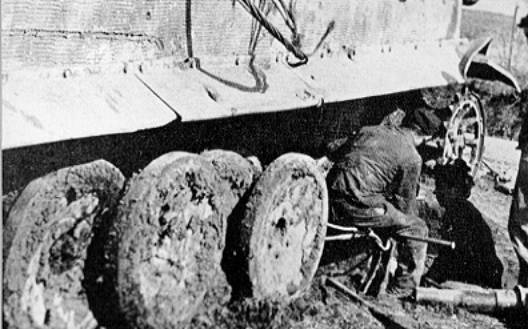 Fitters working on a Tiger's suspension in the mud. Notice how it congeals around the road wheels and imagine the difficulties of handling heavy compo